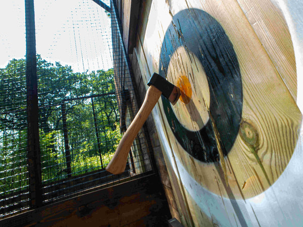 closeup of woman about to throw an axe at a target