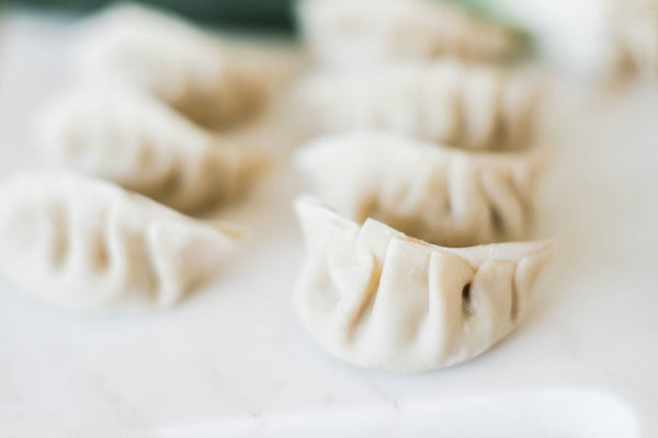A platter of crispy pan-fried dumplings served with dipping sauce and pickled ginger.jpg