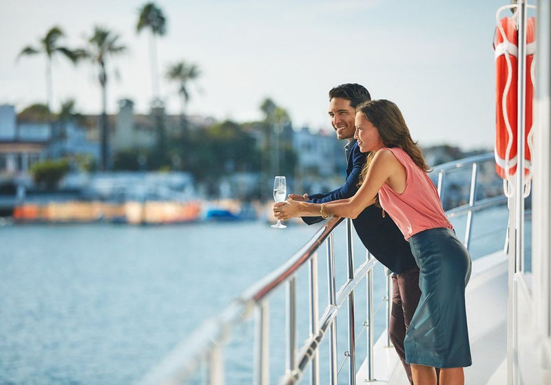 couple-with-champagne-looking-over-railing-to-water