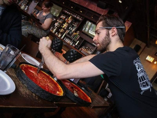 deep dish pizza being cut