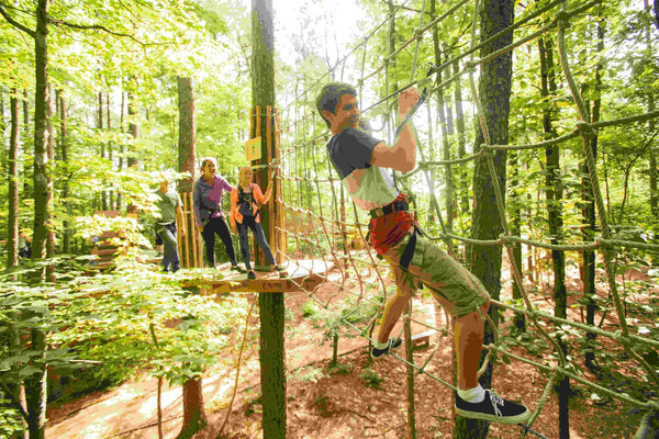 girl in purple preparing to cross bridge at ropes course
