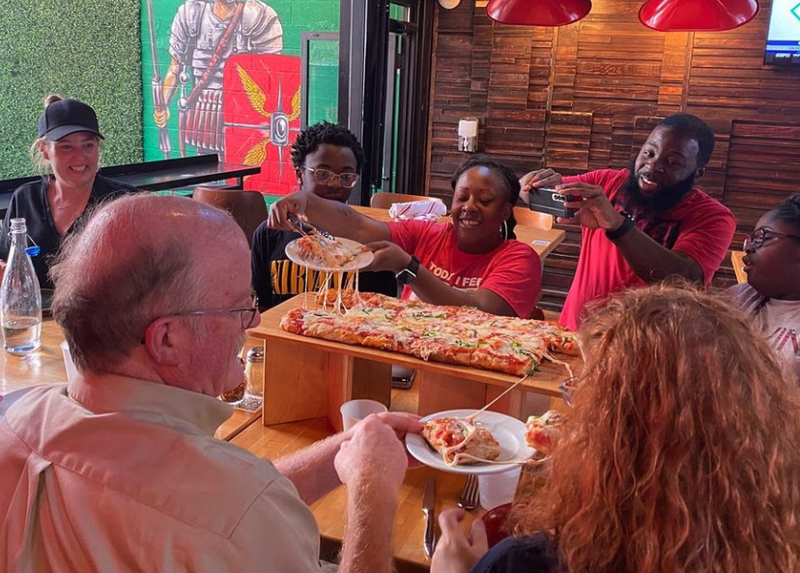 Groups grabbing pizza from tray