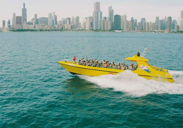 large group with their arms up on speedboat