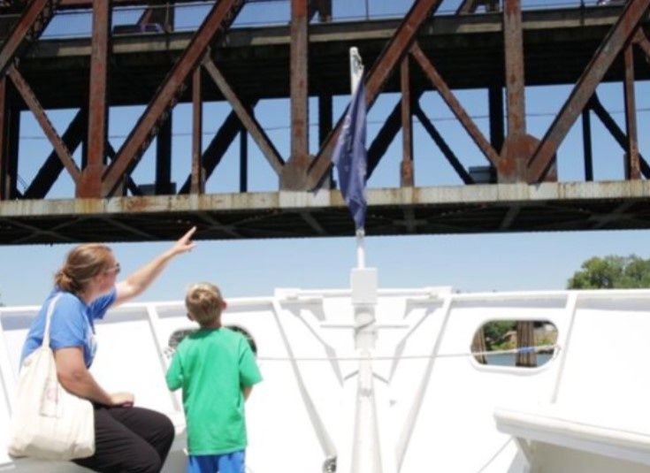 mother-and-child-on-front-of-boat-going-under-a-bridge