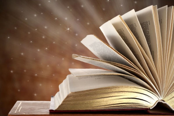 headphones on a book with light and stars behind