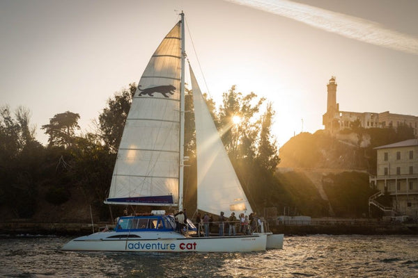 sailboat in the sunset with bridge in background