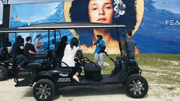 two black golf carts in front of mural