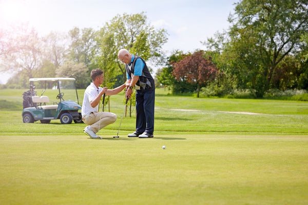 2 men on gold course putting