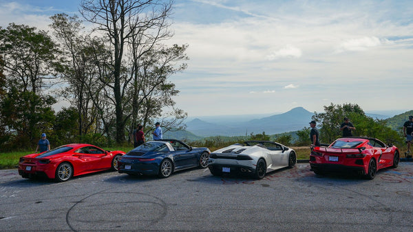 4 luxury cars parked at a lookout