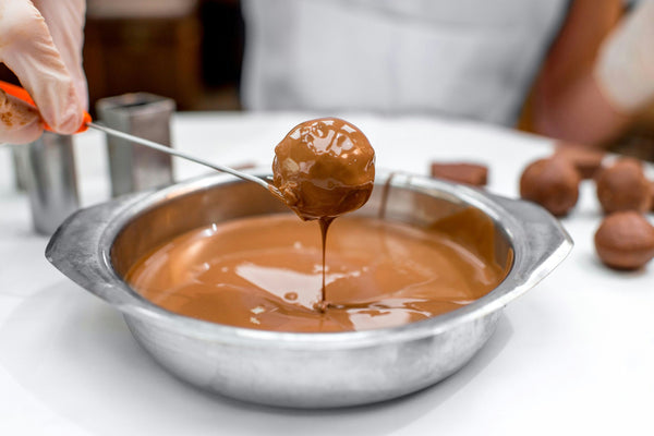 a person dipping a chocolate in caramel.jpg