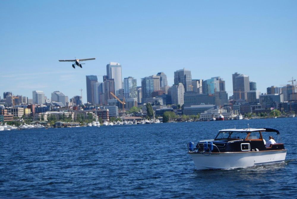 airplane-flying-over-city-with-boat-cruising