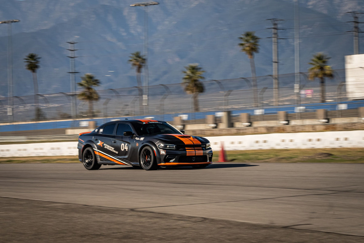 black-and-orange-car-drivng-on-a-track-with-palm-trees