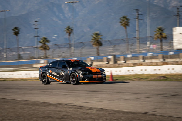 black-and-orange-car-drivng-on-a-track-with-palm-trees
