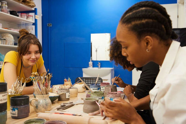 women painting clay mugs