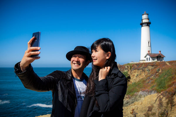 couple-taking-selfie-with-lighthouse-jpg
