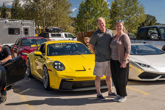 couple standing with yellow car