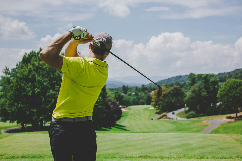 swinging golf club on the green