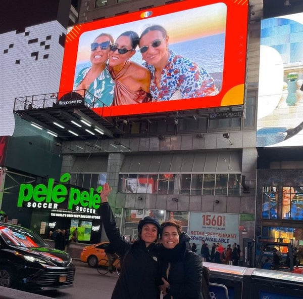 friends standing under photo on billboard
