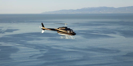 helicopter flying over water with mountain background