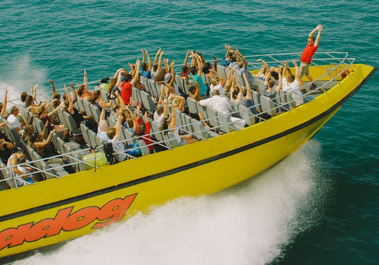large group with their arms up on speedboat