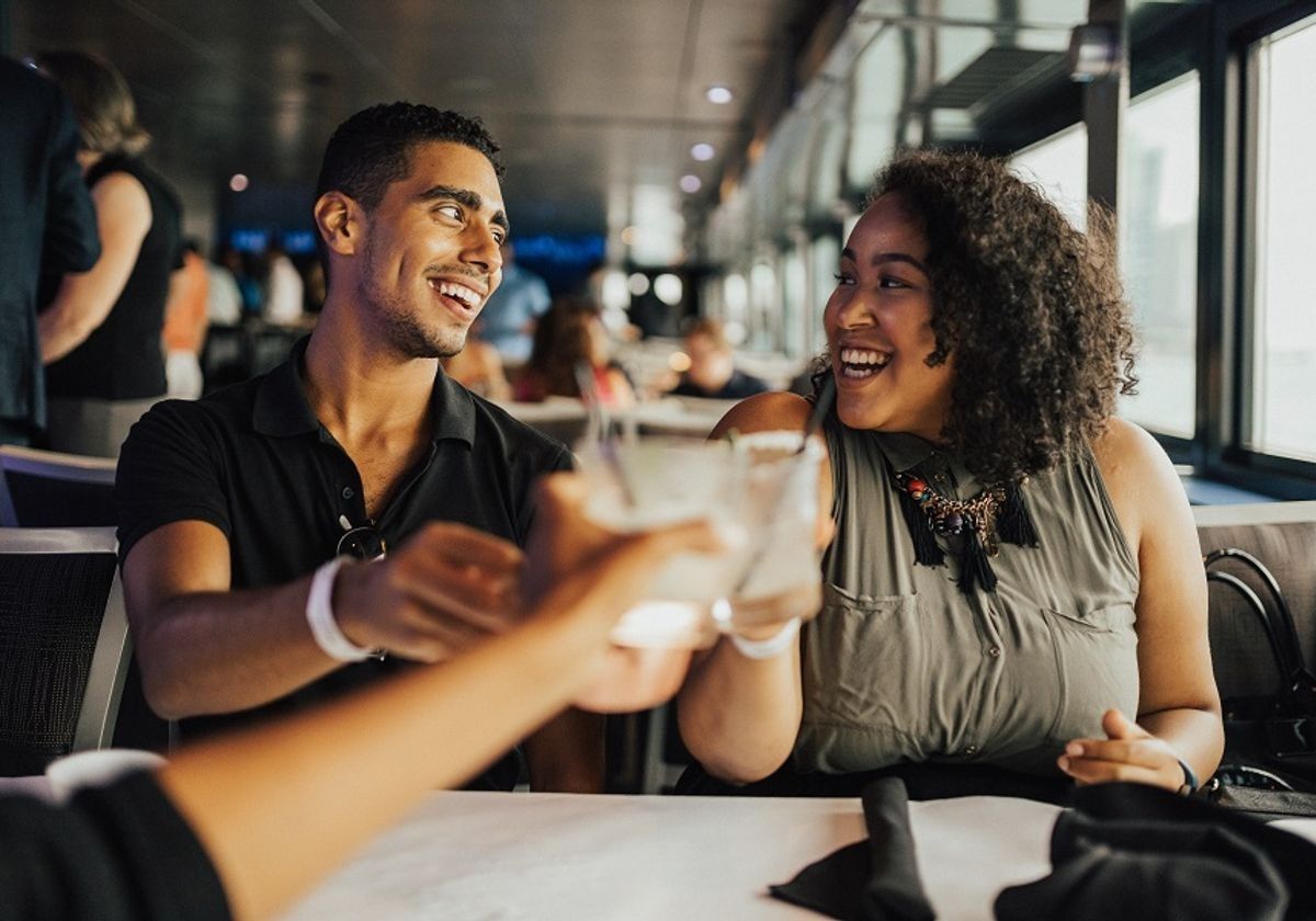 man-and-woman-smile-at-each-other-as-they-toast-with-friend