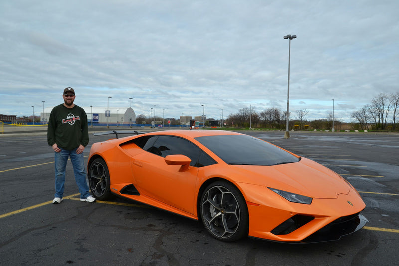 man standing with orange super car