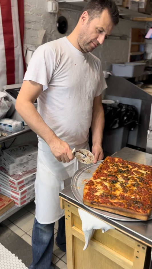 man cutting deep dish pizza