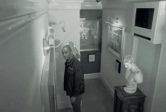 man on surveillance camera with a marble bust behind him