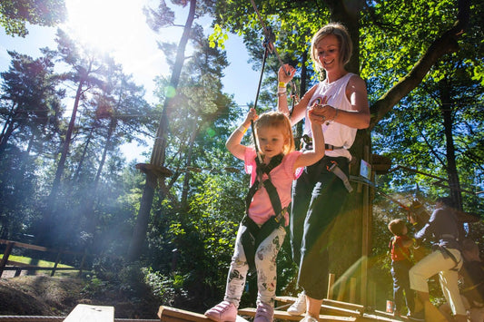 mother helping toddler on ropes course