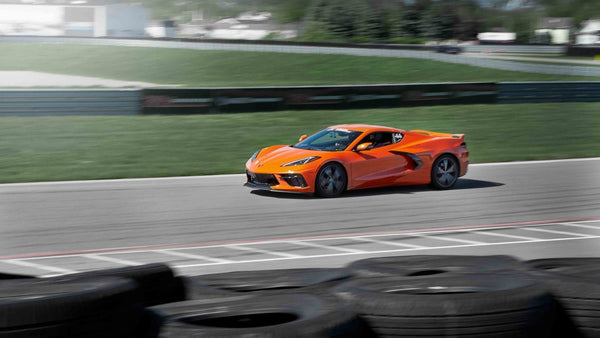 orange corvette driving on track and tires stacked