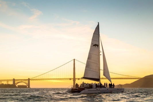 sailboat in the sunset with bridge in background