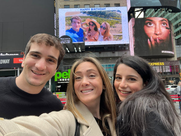 friends standing under photo on billboard