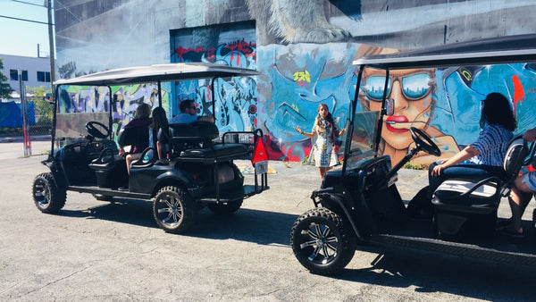 two golf carts in front of tour guide on art tour