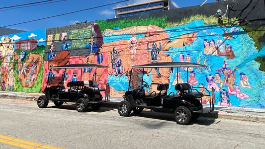 two black golf carts in front of mural