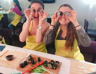 two girls putting sushi to their eyes
