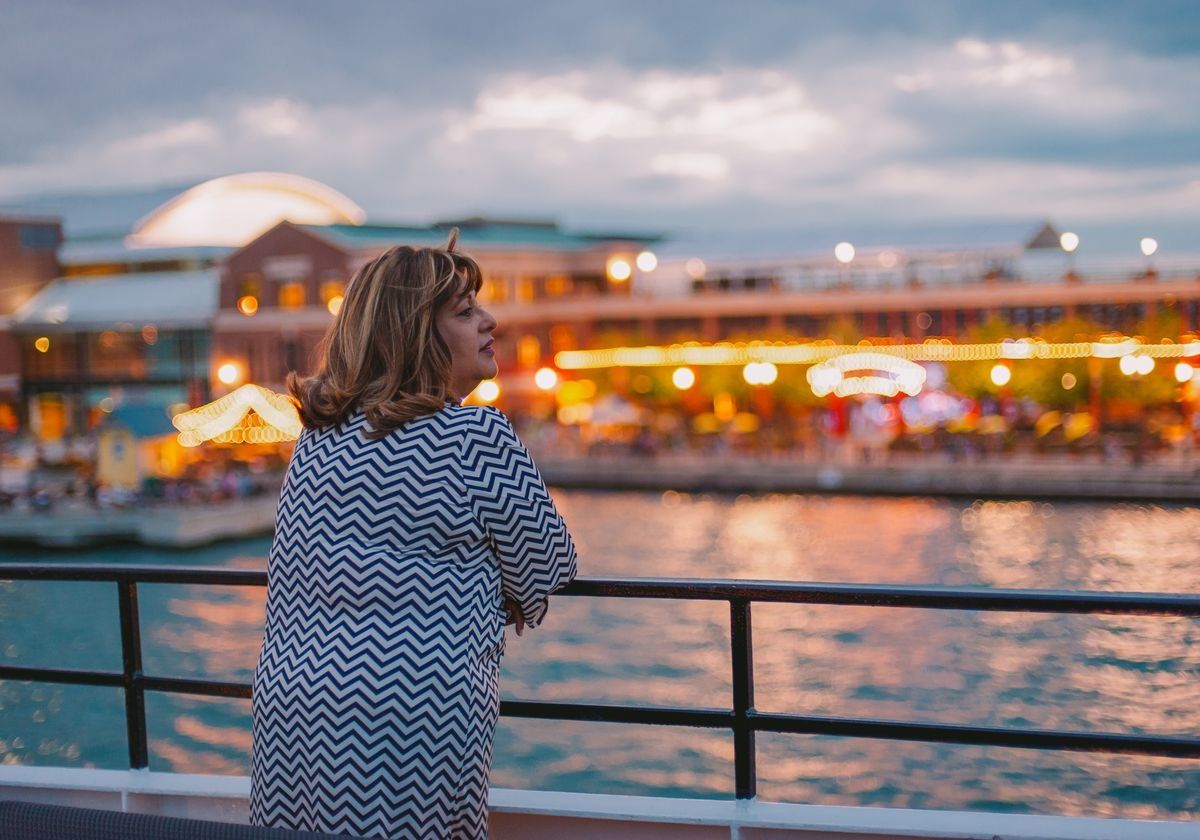 woman-looking-out-from-boat-to-chicago-lit-up-at-night