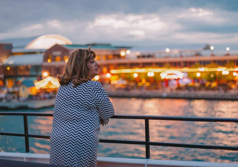 woman-looking-out-from-boat-to-chicago-lit-up-at-night
