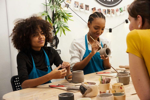 women painting clay mugs