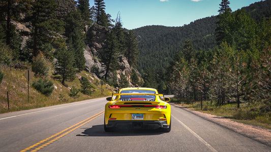 yellow car driving through mountains