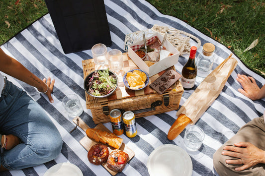 food sitting on and around picnic basket on blanket