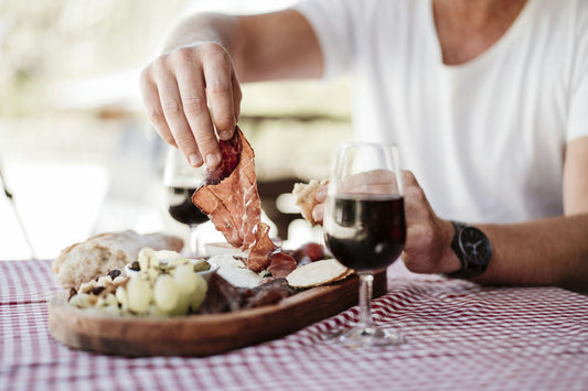 person in tshirt getting picnic food with wine on table